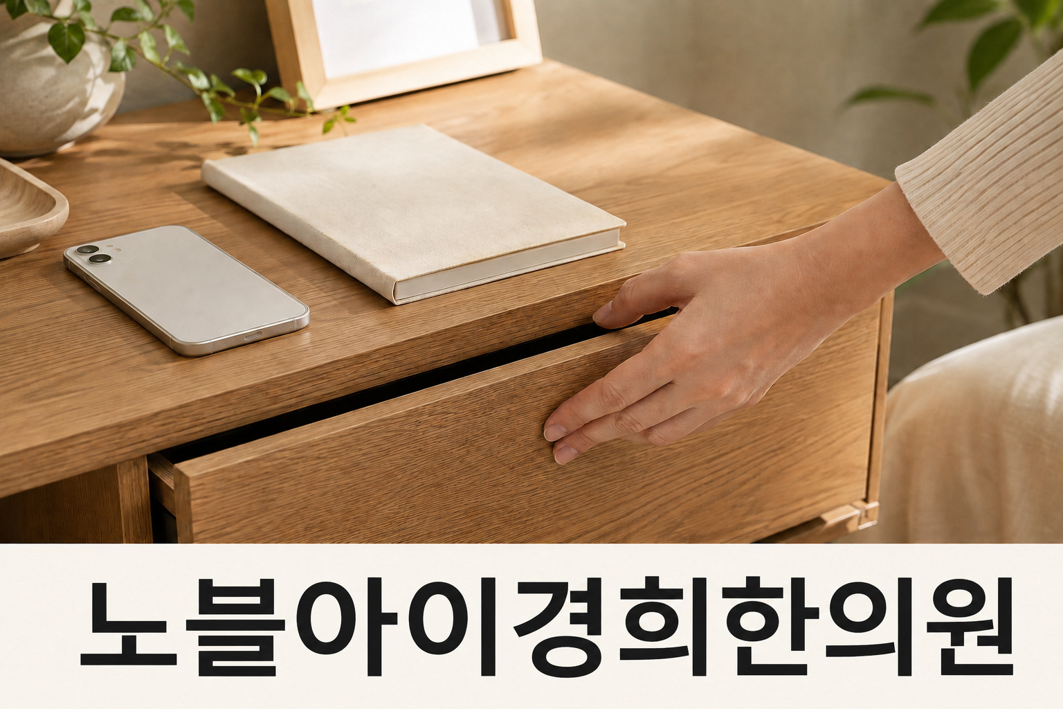 휴대전화와 기록장이 놓인 책상에서 서랍을 닫는 손